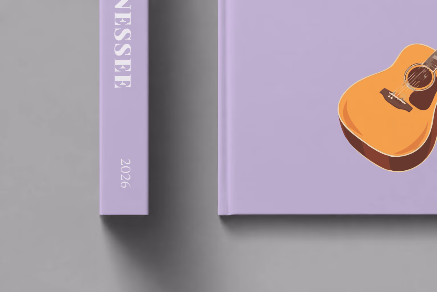 Tennessee hardcover photo book with the illustrated cover of an acoustic guitar on lilac, shown close up beside its spine on a pale grey studio surface