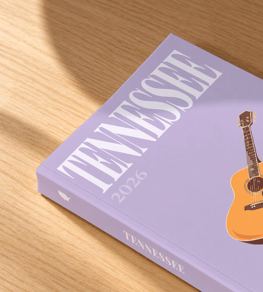 Tennessee softcover photo book with the illustrated cover of an acoustic guitar on lilac, lying on an oak desk in dappled afternoon sunlight