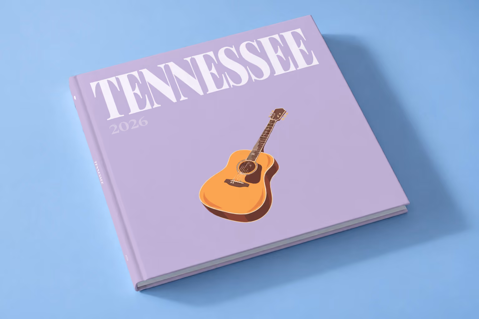 Tennessee square hardcover photo book with the illustrated cover of an acoustic guitar on lilac, lying on a pale blue studio backdrop