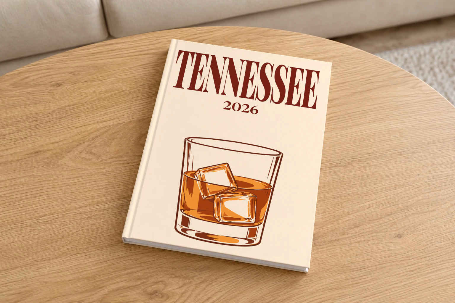 Tennessee hardcover photo book with the illustrated cover of a glass of Tennessee whiskey on the rocks on pale apricot, on a round oak coffee table in a bright living room