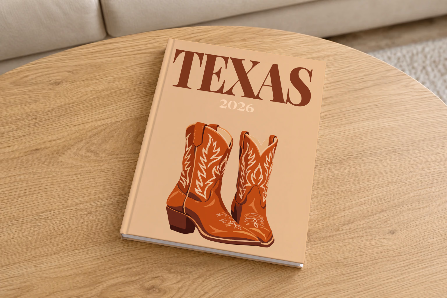 Texas hardcover photo book with the illustrated cover of a pair of brown leather cowboy boots on tan, on a round oak coffee table in a bright living room
