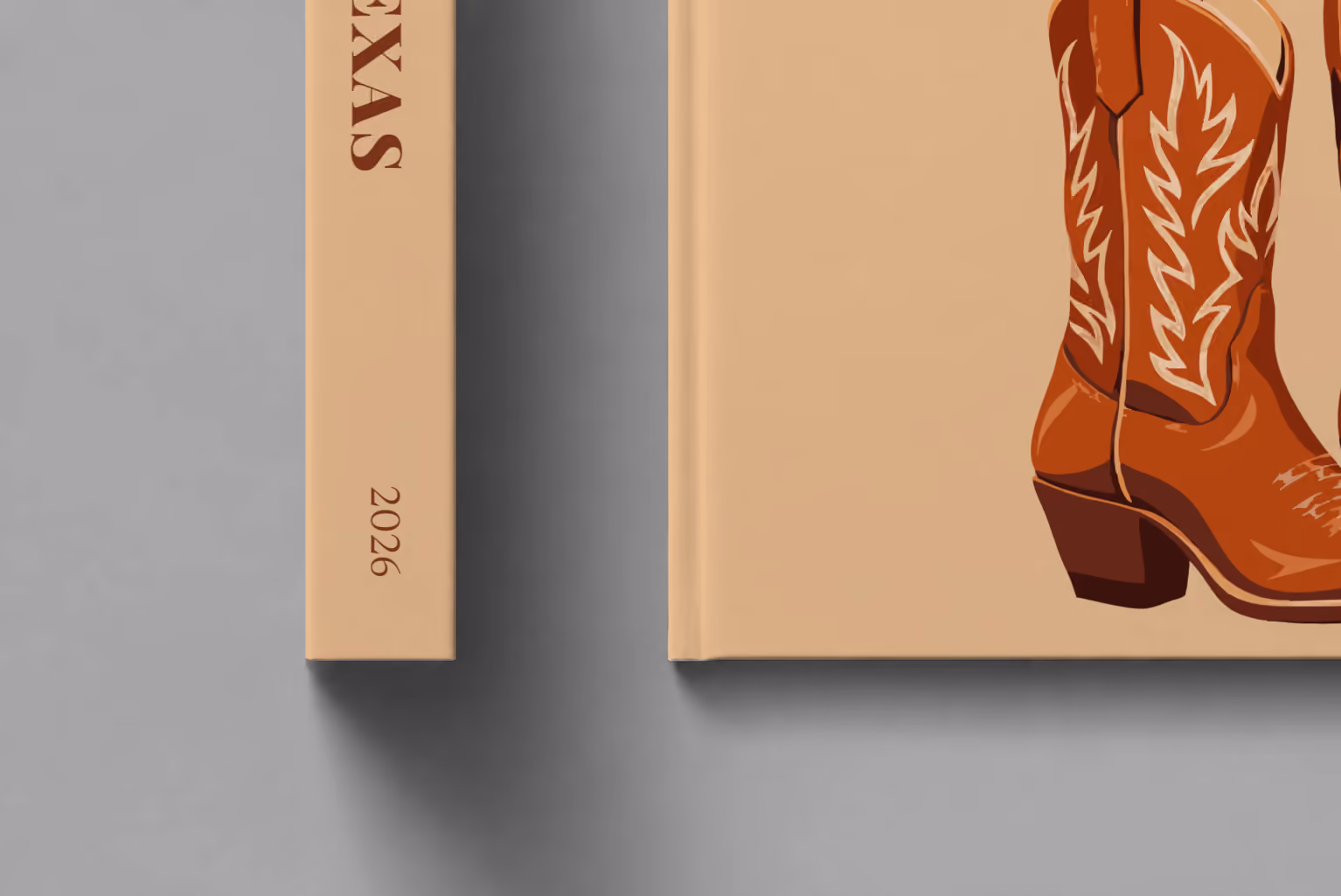 Texas hardcover photo book with the illustrated cover of a pair of brown leather cowboy boots on tan, shown close up beside its spine on a pale grey studio surface