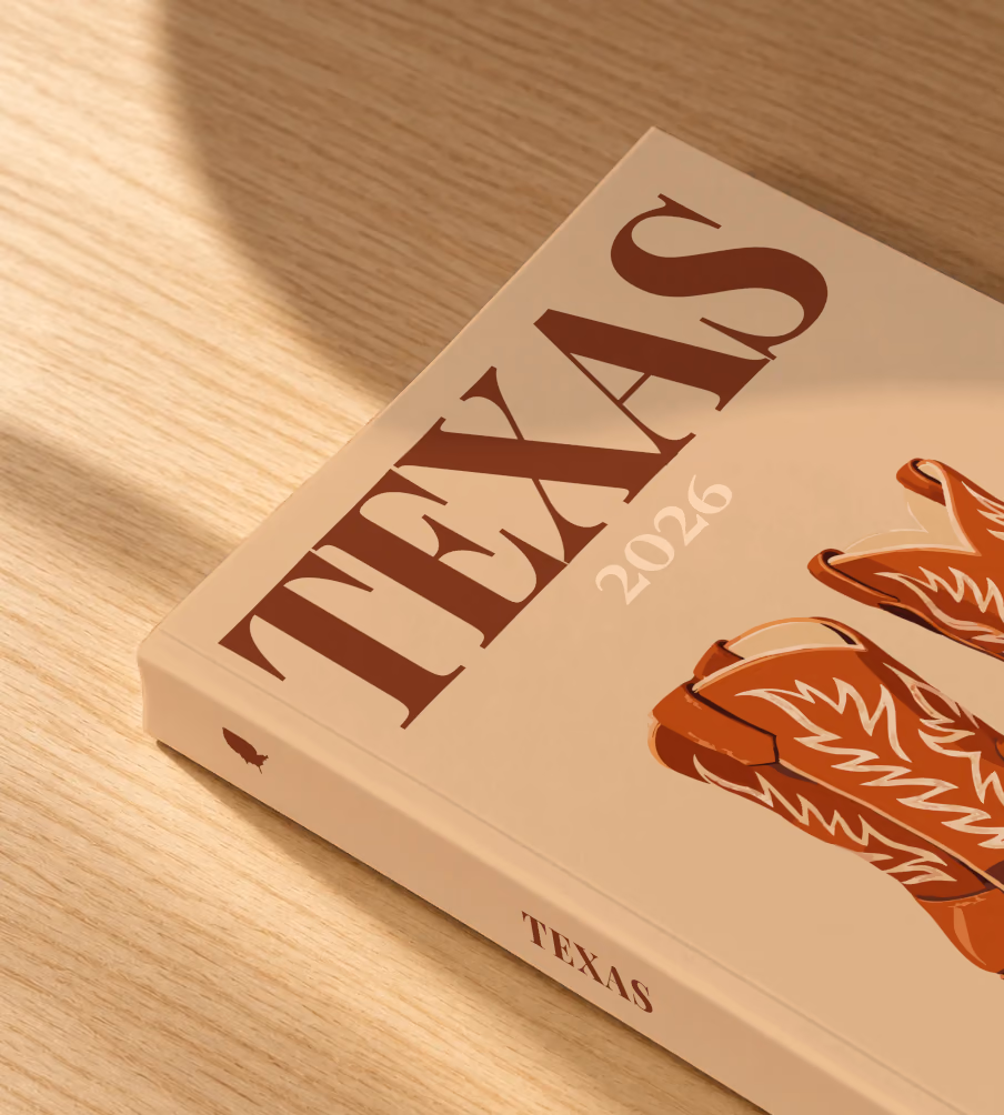Texas softcover photo book with the illustrated cover of a pair of brown leather cowboy boots on tan, lying on an oak desk in dappled afternoon sunlight