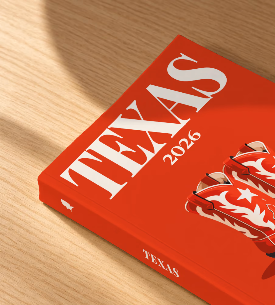 Texas softcover photo book with the illustrated cover of a pair of red cowboy boots with white stars on red, lying on an oak desk in dappled afternoon sunlight