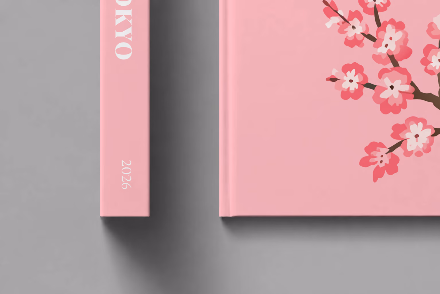 Tokyo hardcover photo book with the illustrated cover of a cherry blossom branch on pink, shown close up beside its spine on a pale grey studio surface