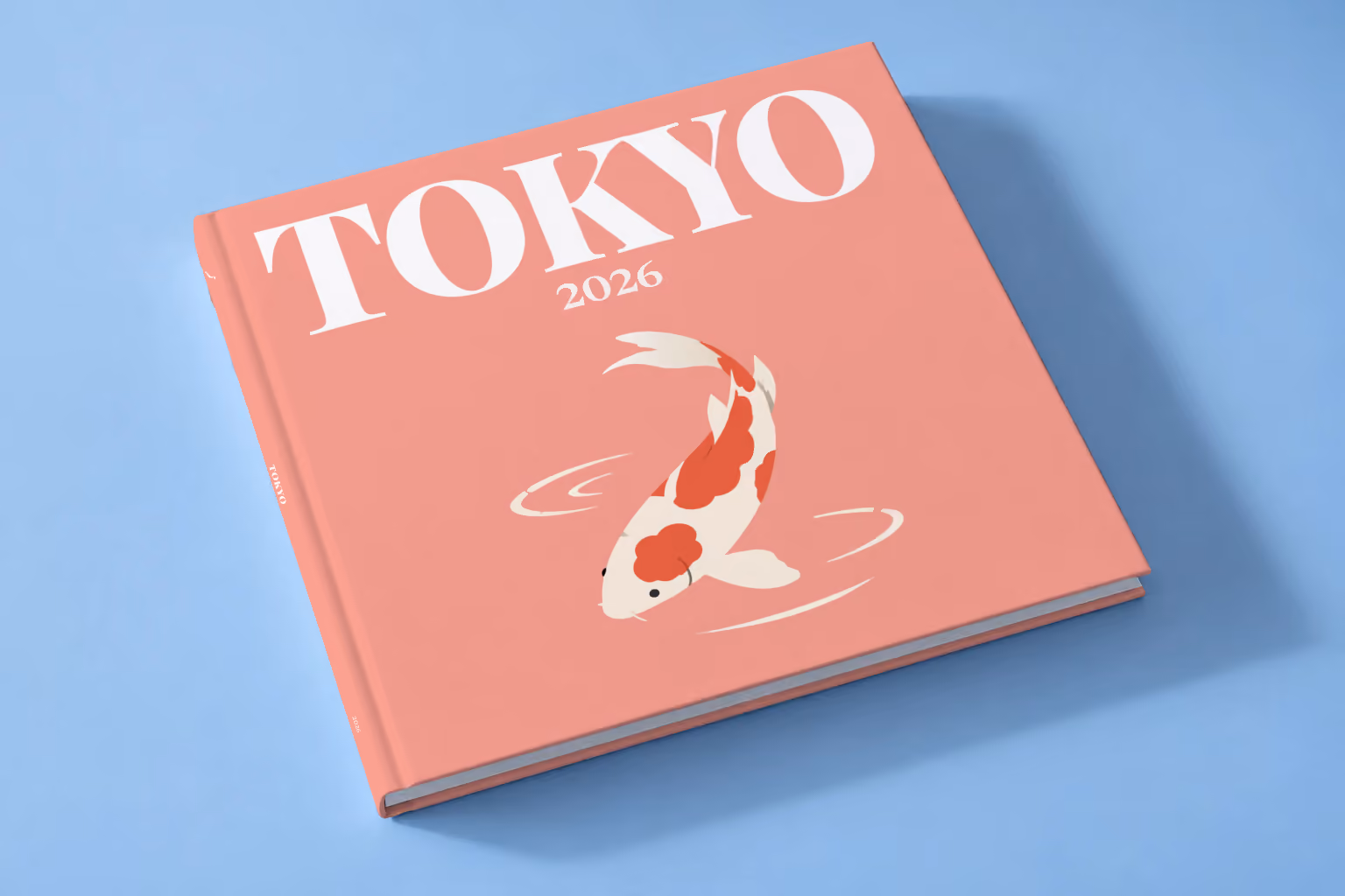 Tokyo square hardcover photo book with the illustrated cover of a koi on coral pink, lying on a pale blue studio backdrop