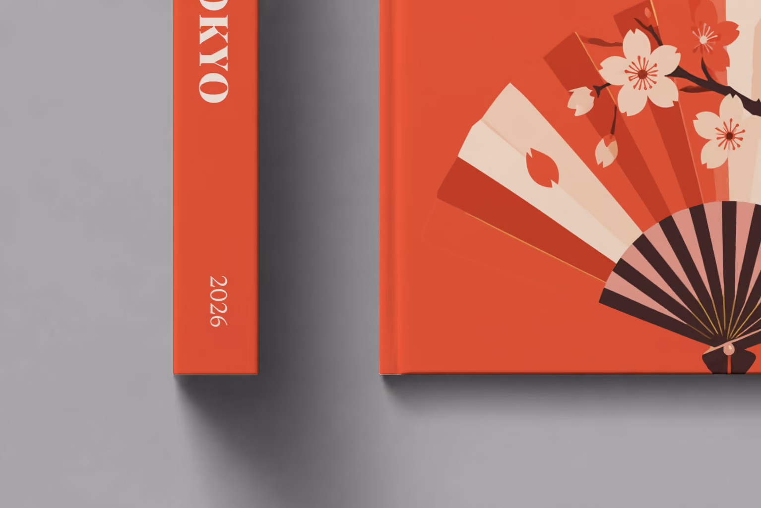 Tokyo hardcover photo book with the illustrated cover of a folding fan with cherry blossom on red, shown close up beside its spine on a pale grey studio surface
