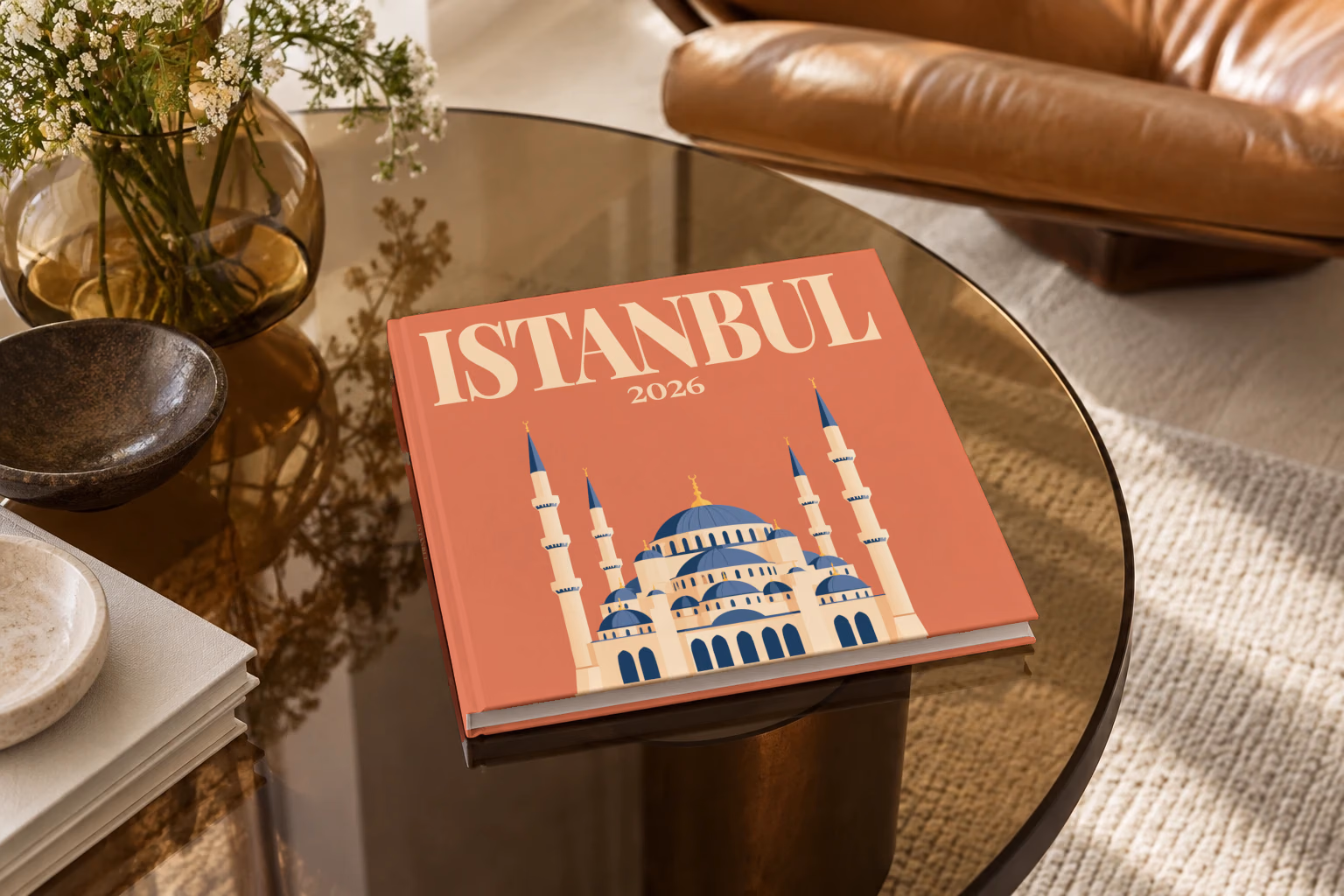 Turkey square hardcover photo book with the Istanbul illustrated cover of the domes and minarets of the Blue Mosque on terracotta, on a smoked glass coffee table beside a leather armchair in warm afternoon light
