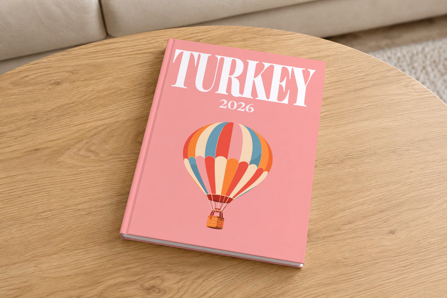 Turkey hardcover photo book with the illustrated cover of a striped Cappadocia hot air balloon on pink, on a round oak coffee table in a bright living room