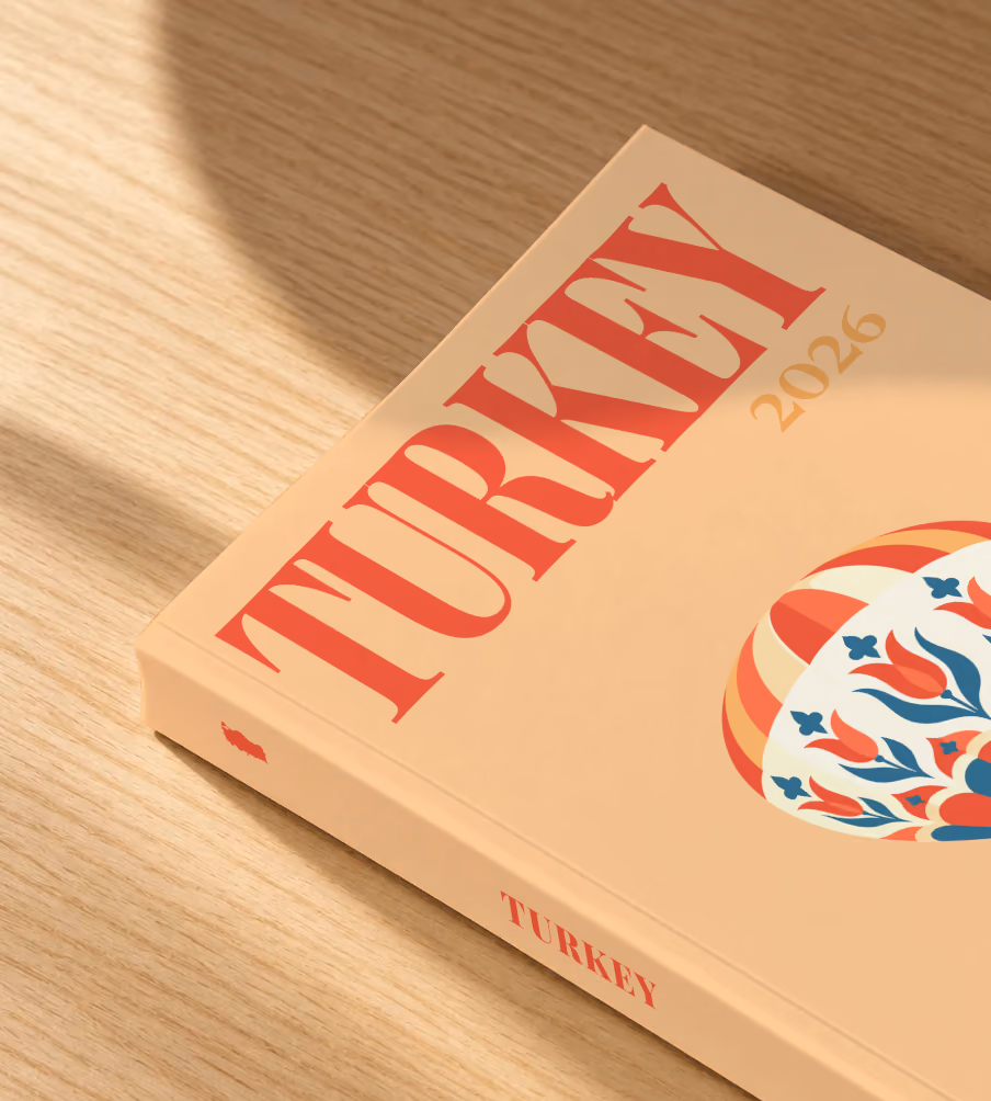 Turkey softcover photo book with the illustrated cover of a hot air balloon patterned with Turkish tulips on peach, lying on an oak desk in dappled afternoon sunlight