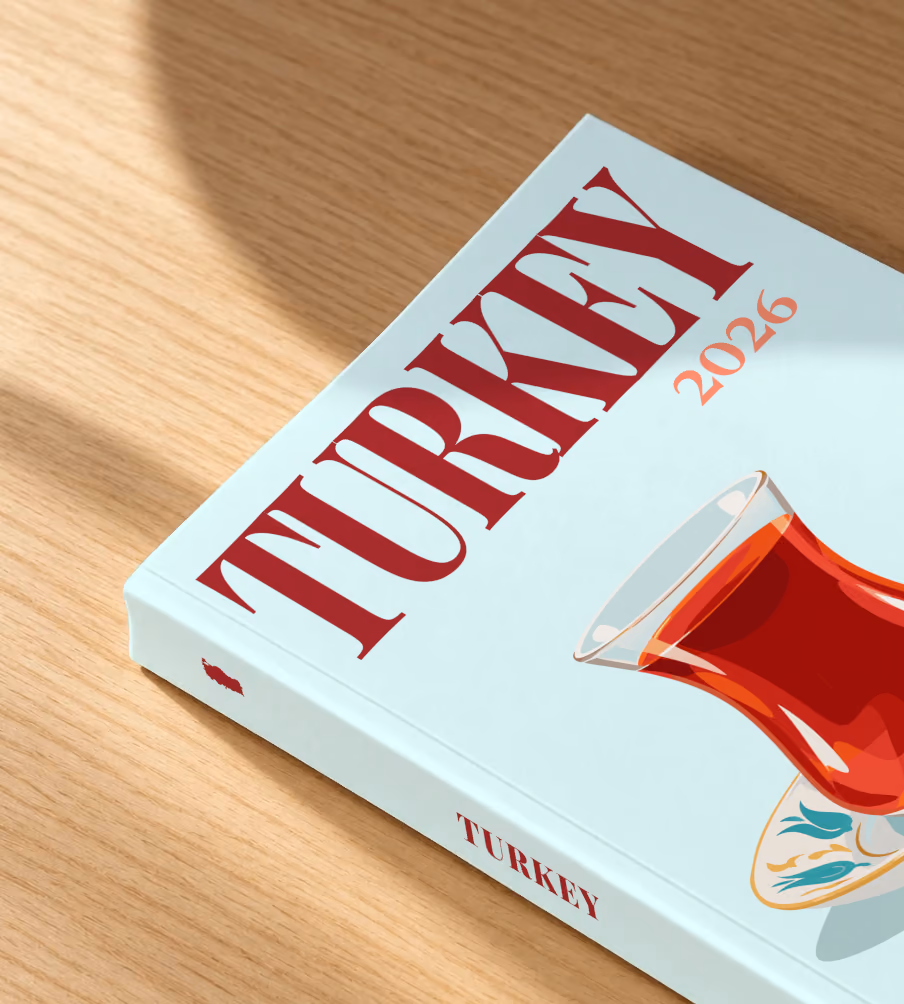 Turkey softcover photo book with the illustrated cover of a tulip glass of Turkish tea on a saucer with a red tulip on pale aqua, lying on an oak desk in dappled afternoon sunlight