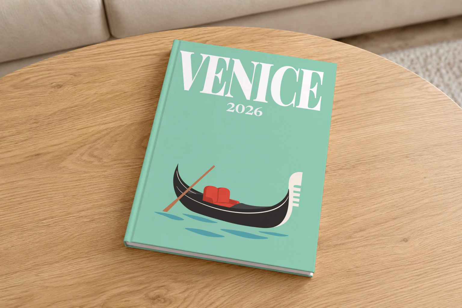 Venice hardcover photo book with the illustrated cover of a gondola on the lagoon on mint green, on a round oak coffee table in a bright living room