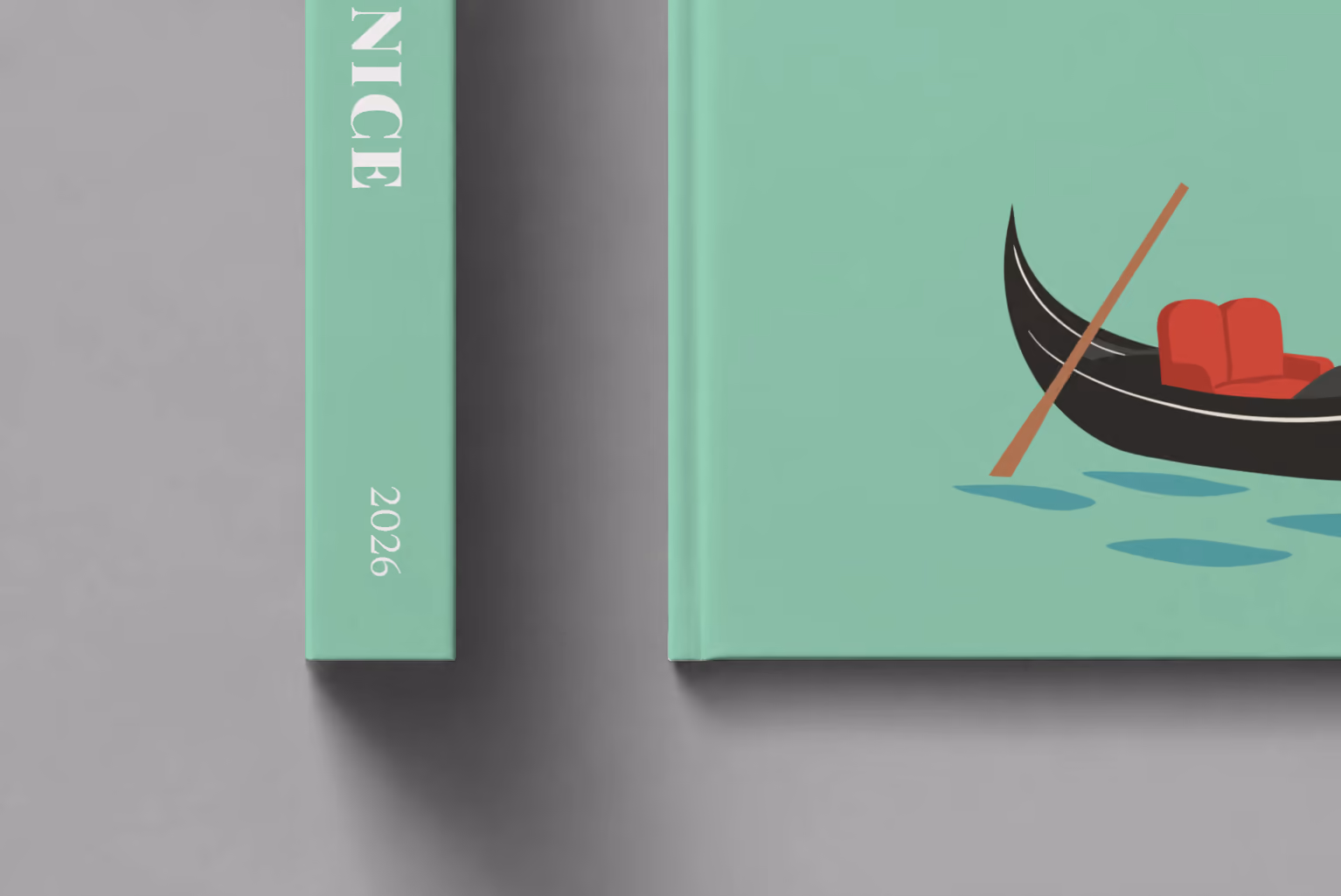 Venice hardcover photo book with the illustrated cover of a gondola on the lagoon on mint green, shown close up beside its spine on a pale grey studio surface