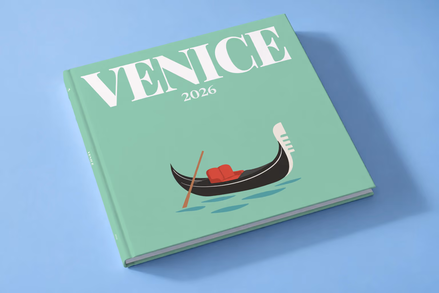 Venice square hardcover photo book with the illustrated cover of a gondola on the lagoon on mint green, lying on a pale blue studio backdrop