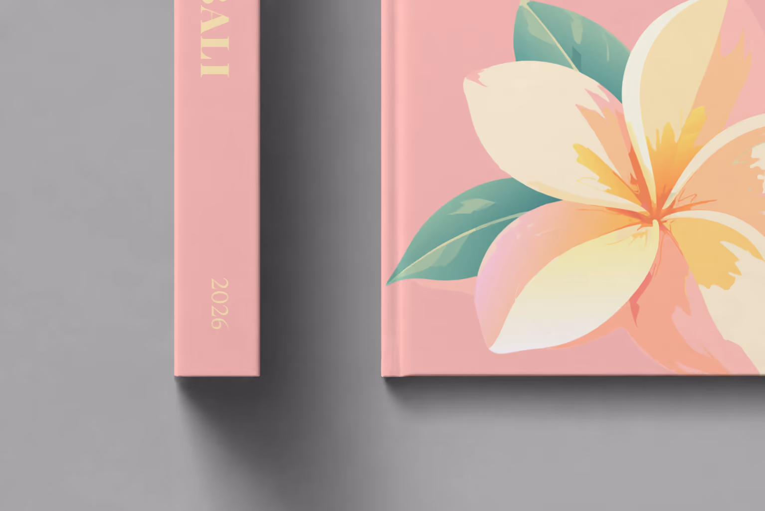 Bali hardcover photo book with an illustrated cover of a frangipani flower, shown close up beside its spine on a pale grey studio surface