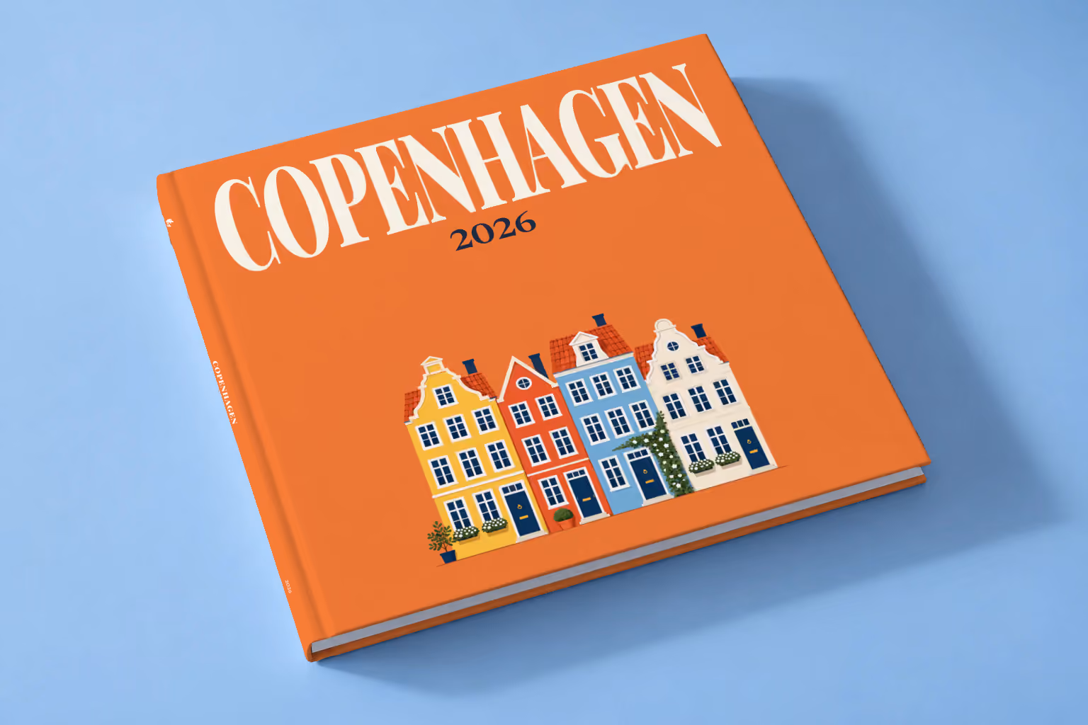 Copenhagen hardcover photo book with an illustrated cover of the colourful Nyhavn houses, lying on a pale blue studio backdrop