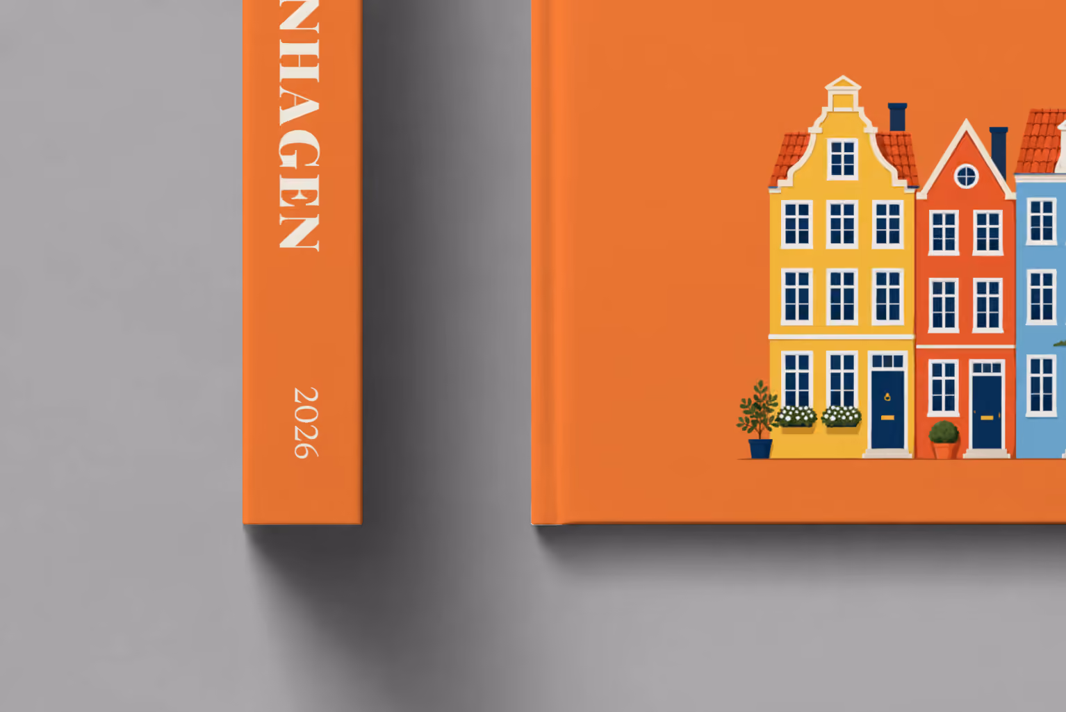 Copenhagen hardcover photo book with an illustrated cover of the colourful Nyhavn houses, shown close up beside its spine on a pale grey studio surface