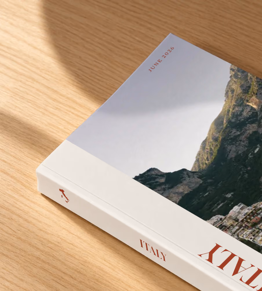 Italy softcover photo book with the Editorial cover, lying on an oak desk in dappled afternoon sunlight