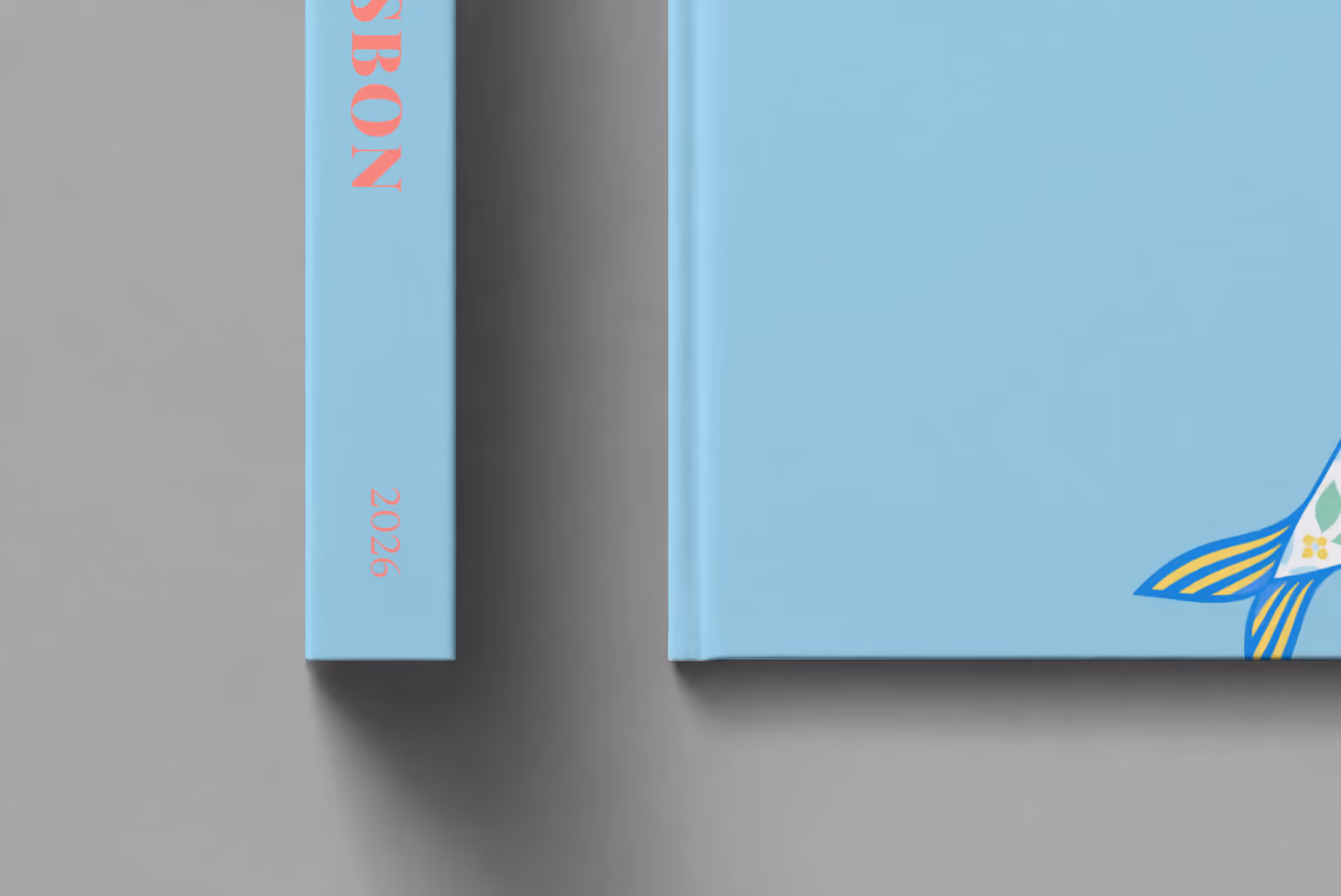 Lisbon hardcover photo book with an illustrated cover of a sardine painted like azulejo tiles, shown close up beside its spine on a pale grey studio surface