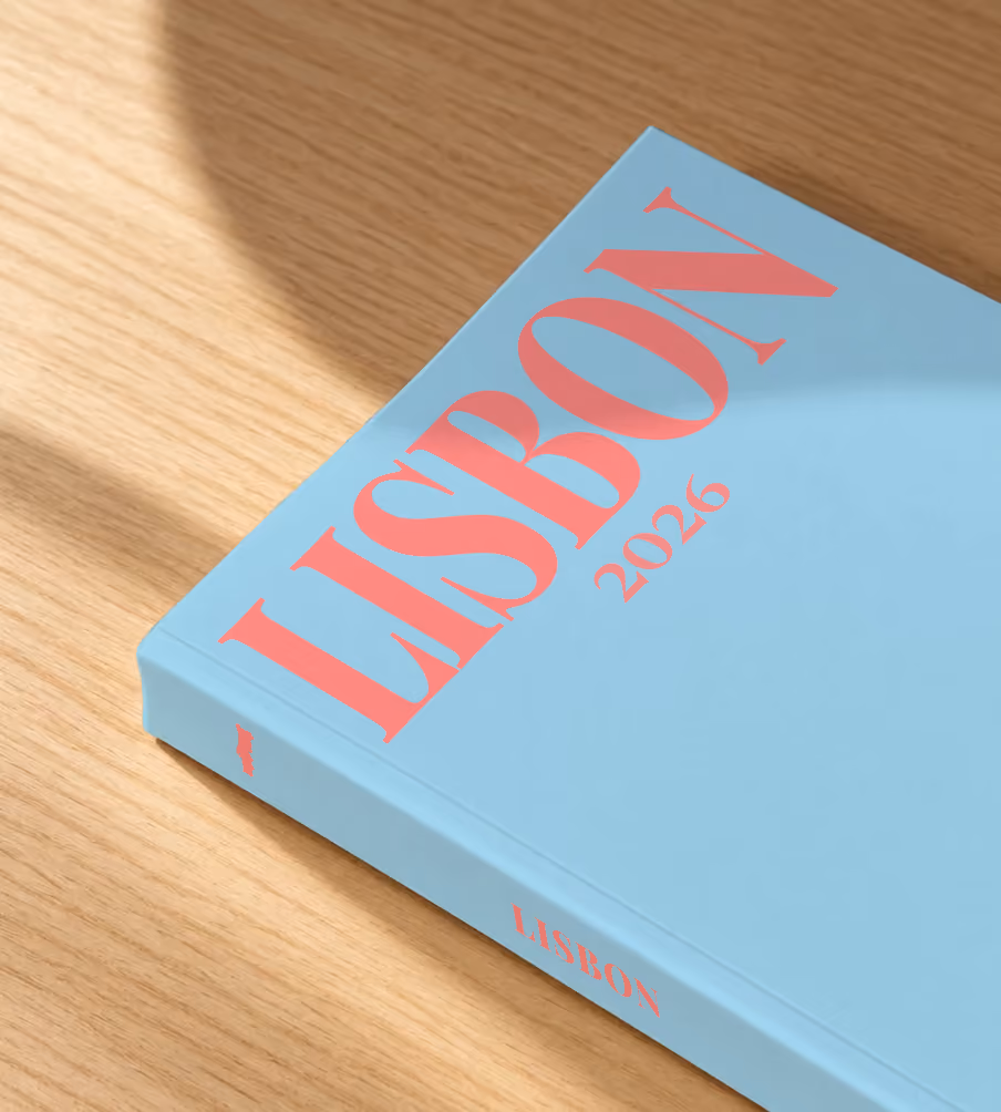 Lisbon softcover photo book with an illustrated cover of a sardine painted like azulejo tiles, lying on an oak desk in dappled afternoon sunlight