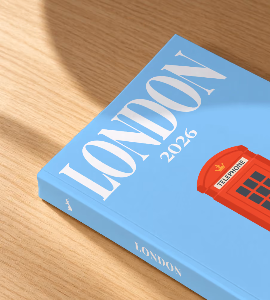 London softcover photo book with an illustrated cover of a red telephone box, lying on an oak desk in dappled afternoon sunlight