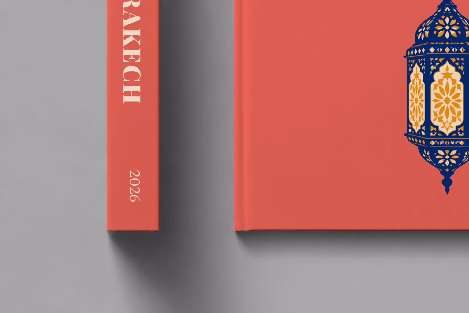 Marrakech hardcover photo book with an illustrated cover of a Moroccan lantern, shown close up beside its spine on a pale grey studio surface