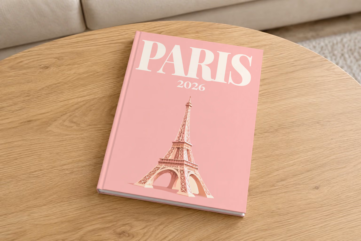 Paris hardcover photo book with an illustrated cover of the Eiffel Tower on blush pink, on a round oak coffee table in a bright living room
