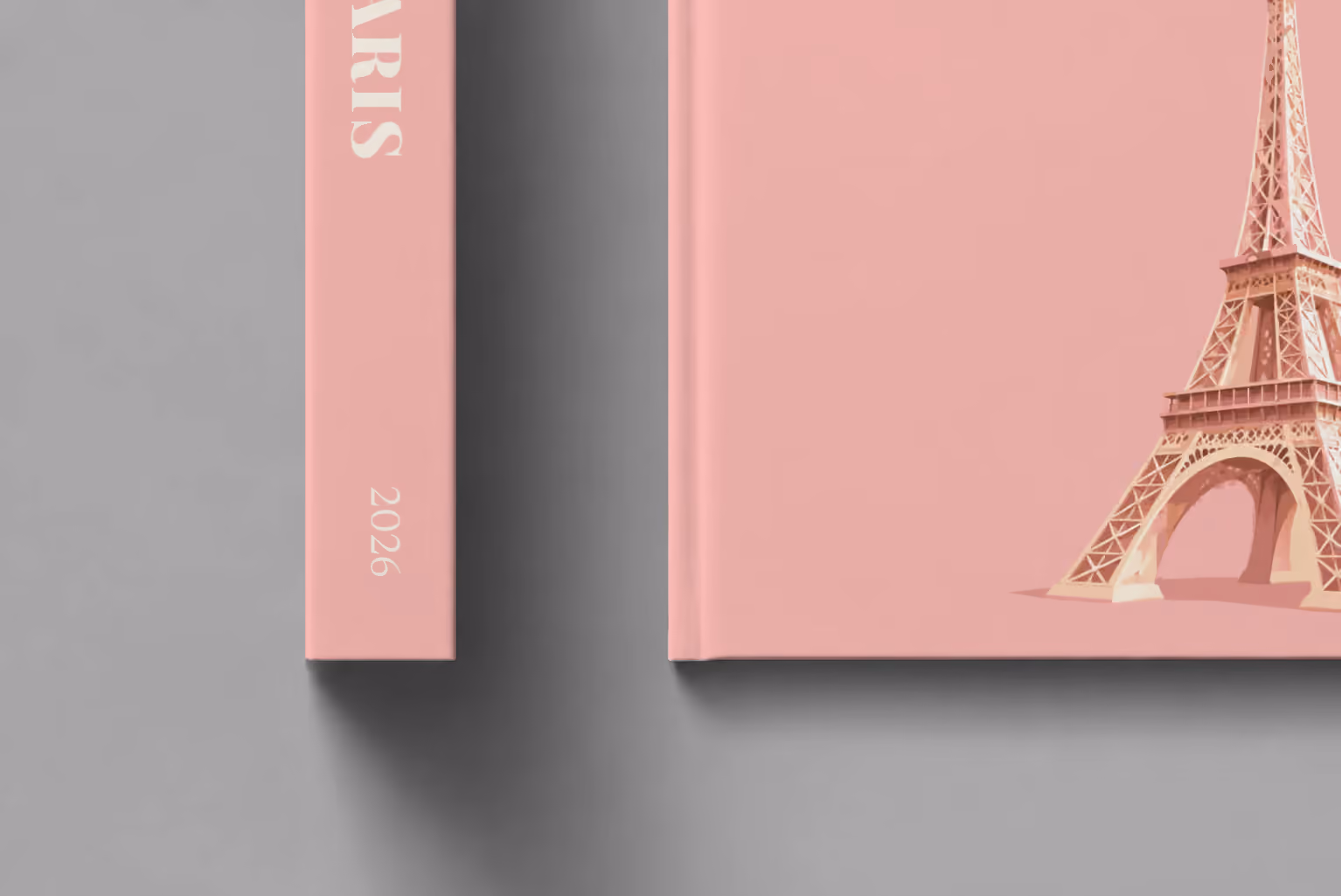 Paris hardcover photo book with an illustrated cover of the Eiffel Tower on blush pink, shown close up beside its spine on a pale grey studio surface