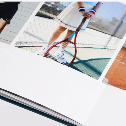 Close up of a layflat photo book page lying flat, printed with a photo of a tennis player with a red racket