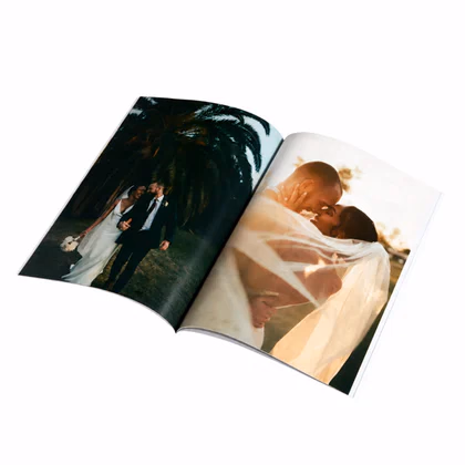 Open softcover photo book with wedding photos of a couple across both pages, its flexible cover bending back