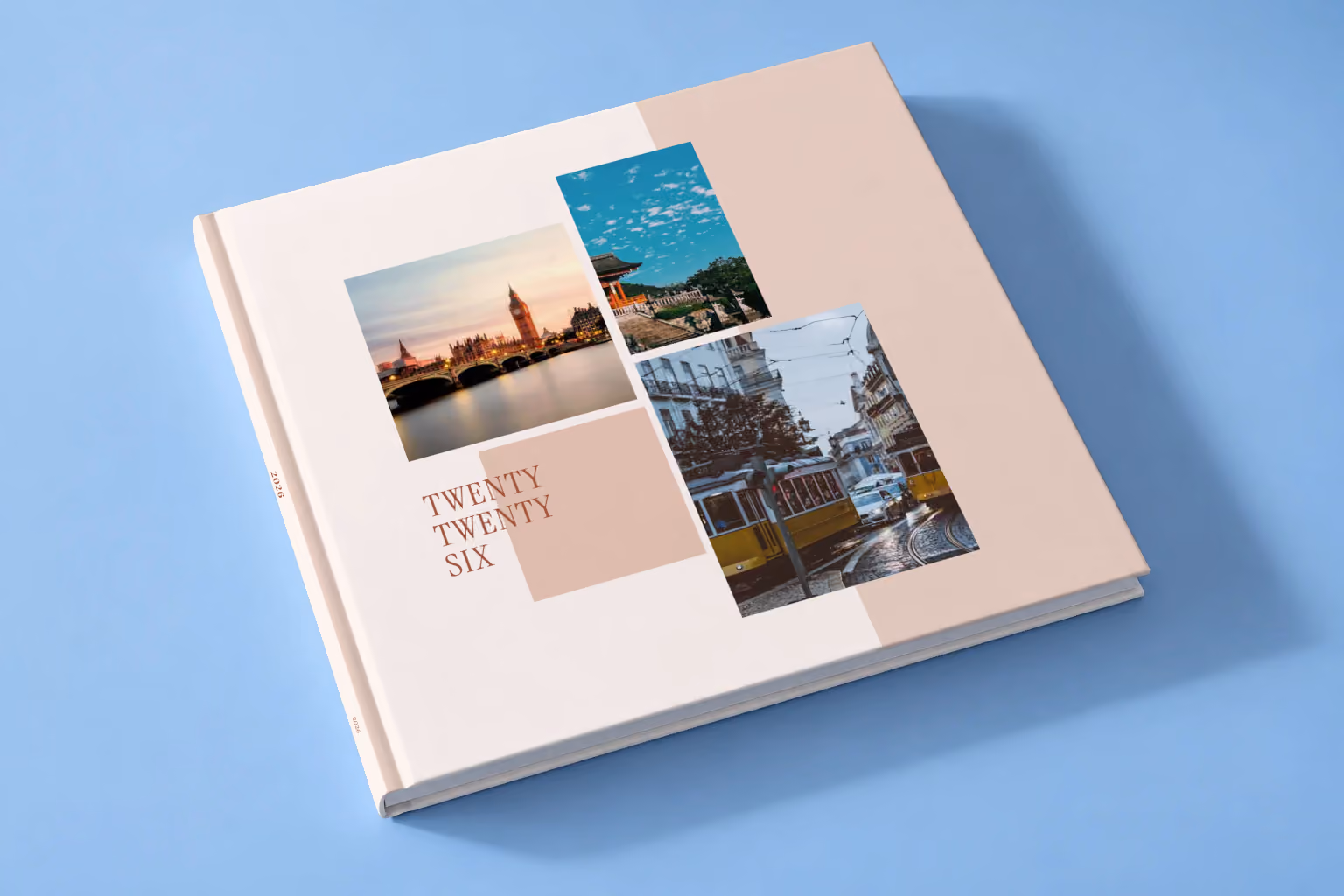 Editorial II year in review square hardcover photo book, a blush editorial cover with three travel photos, lying on a pale blue studio backdrop