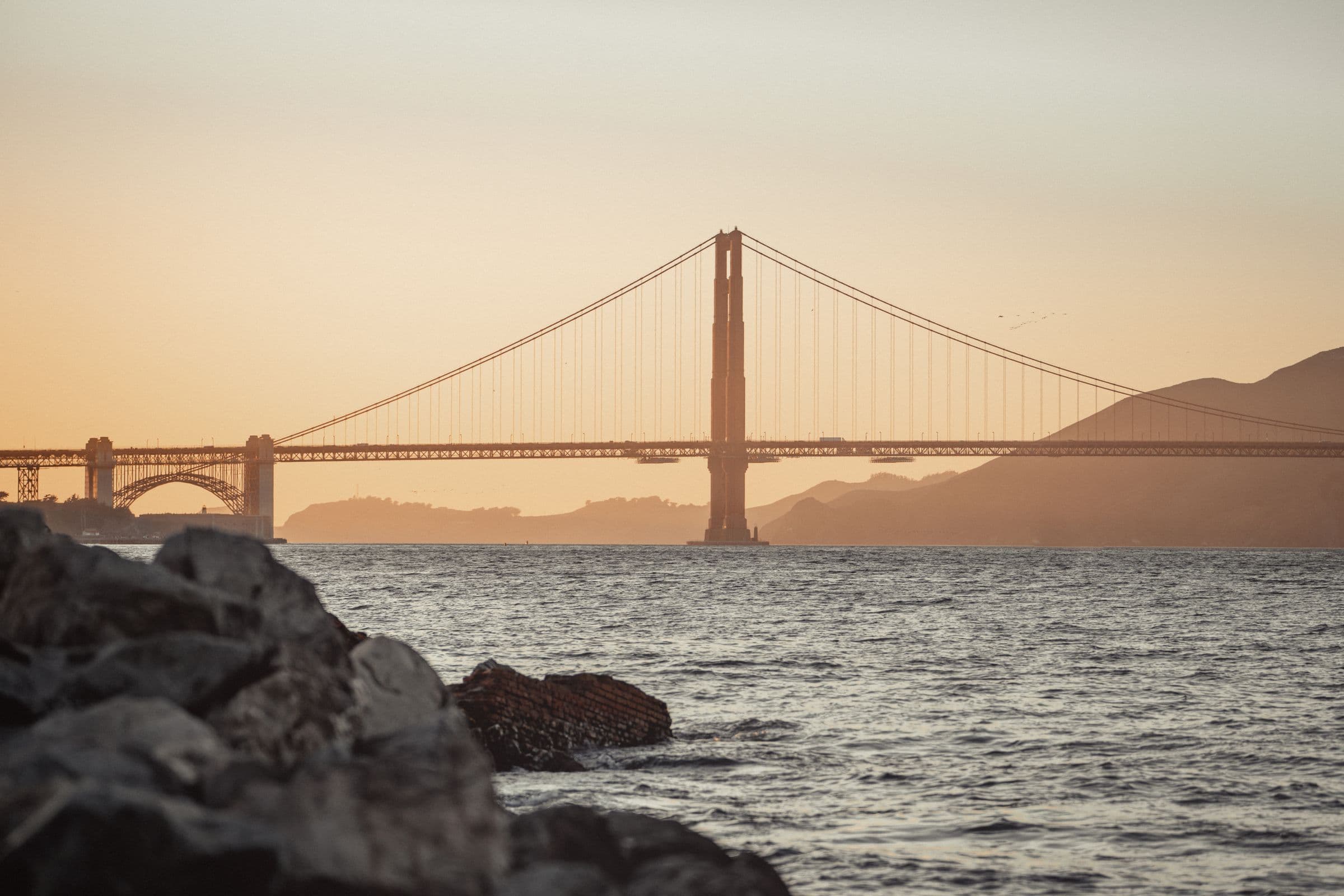 Golden Gate Bridge stretching across San Francisco Bay in warm evening light
