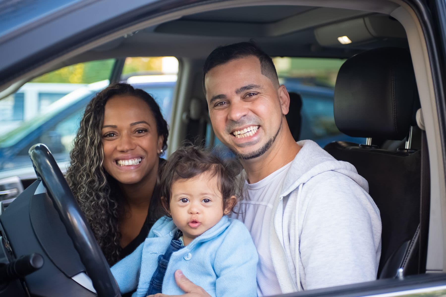 Family smiling together inside a parked car