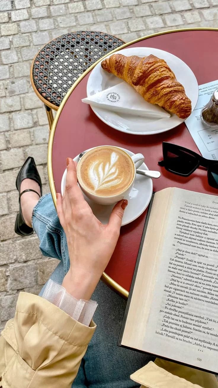 Solo female traveller writing private journal notes beside coffee and a book at a pavement café