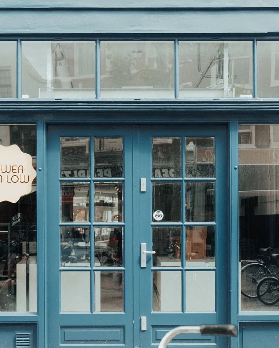 Blue neighbourhood storefront with bicycles reflected in its windows