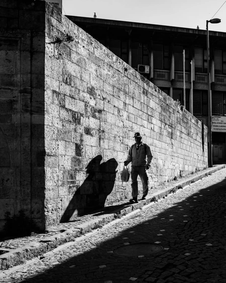 Pedestrian and long shadow on a sunlit historic street