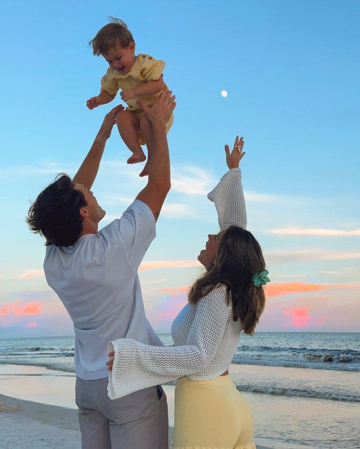 Young family playing together on a beach at sunset