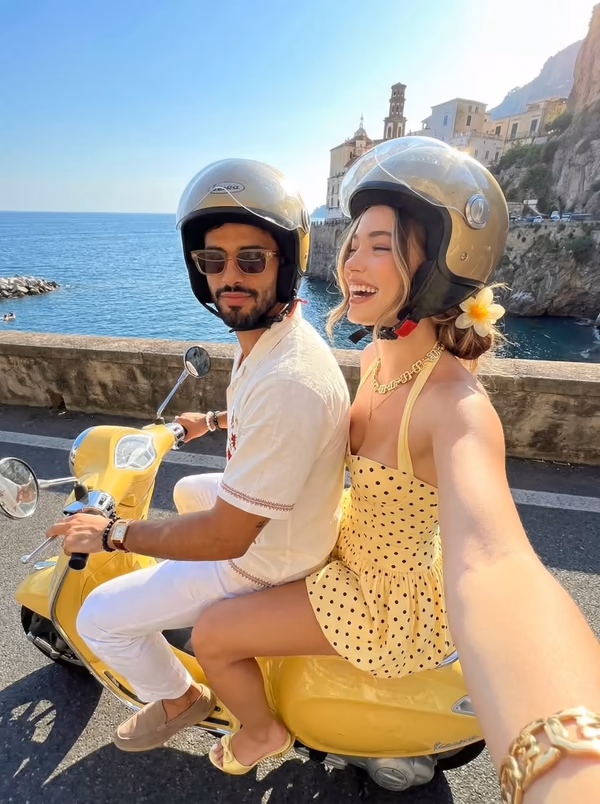 Couple riding a yellow scooter together beside the Amalfi Coast