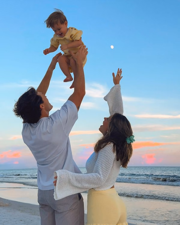 Young family playing together on a beach at sunset