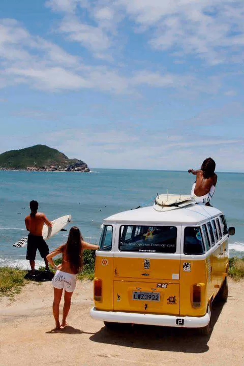 Friends beginning a coastal road trip beside a yellow camper van