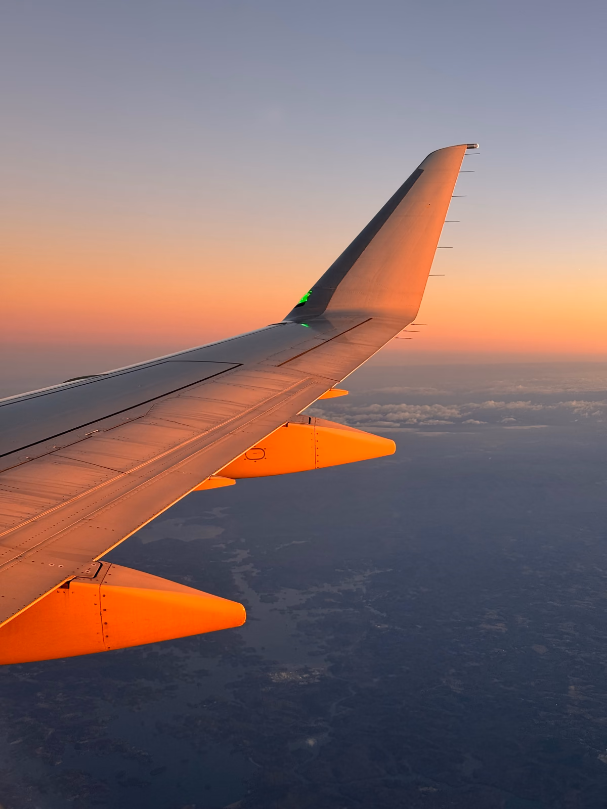 Aeroplane wing glowing orange above the clouds at sunset